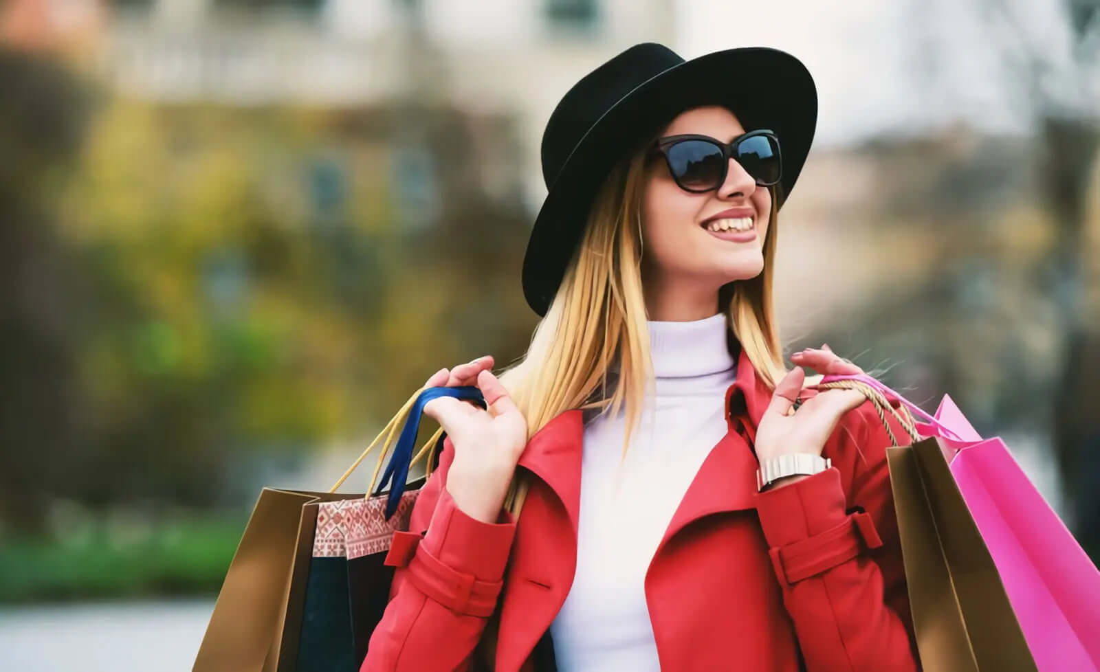 Stylish woman in red coat and black hat holding shopping bags, showcasing the Baliveno Women Collection fashion.